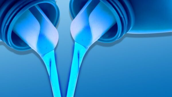 Primer plano de detergente líquido azul cayendo en un dosificador con fondo de lavandería limpia